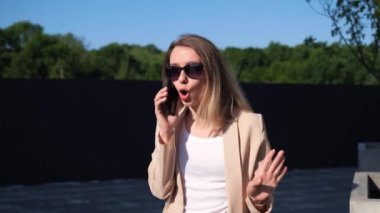 Güneş gözlüklü gergin genç sarışın kadın dışarıda durup kızgın el sallıyor. Öfkeden kudurmuş kız kavgası kötü sözler söylüyor duygusal taciz agresif bağırış.