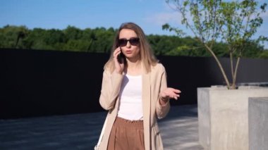 Başarılı bir iş kadını park alanında cep telefonuyla konuşuyor. İş kadını dışarıda cep telefonuyla konuşuyor iş görüşmelerine cevap veriyor. Kadın profesyonel telefon görüşmesi yapıyor.