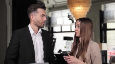 Business people having conversation in hotel lobby. Serious business partners talking indoors. Corporate employees discussing project in the hall. Business couple working. Marketing agency team