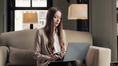 Portrait of serious businesswoman working on laptop in hotel restaurant during work trip. Close up confident woman reading message news on notebook. Female manager typing on laptop in caffe indoor
