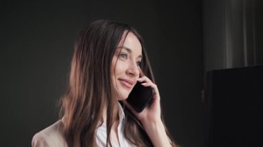 Otel odasında akıllı telefondan konuşan iş kadınına yakın çekim. Gülümseyen iş kadını ofisteki cep telefonunu arıyor. Dost canlısı bir bayanın portresi iş konuşmasında.