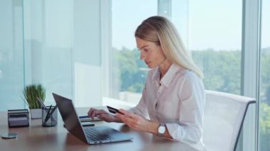 Excited businesswoman entering data from credit card to laptop showing positive success emotions winner sitting at the workplace in the office. Online shopping Payment on internet banking Celebration