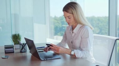 Young business woman entering credit card number on laptop, paying utility bills. Female hands holding Credit Card makes purchase on web site, use e-bank app sit at table indoor. Easy secure payment