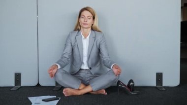 Stressful woman employee in lotus position sit on the floor without shoes closed eyes meditating take break during work keep mental balance patience yoga practices no stress feel zen balance