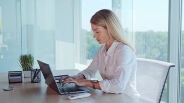 Businesswoman employee feels suffocated working on laptop turn on air conditioner using remote control, cooling system or humidifier. Concentrated woman sets a comfortable temperature Hot summer time
