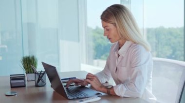 Businesswoman employee feels suffocated working on laptop turn on air conditioner using remote control, cooling system or humidifier. Concentrated woman sets a comfortable temperature Hot summer time