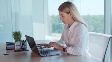 Confident employee woman feeling cold working with laptop rubs with hands, turn off air conditioning. Office worker sitting on workplace suffering from low indoors temperature, ventilation system