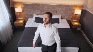 Businessman falls on soft bed with arms raised feels happy, relish fresh beddings linen, enjoy holidays, accommodation in hotel. Relax, vacation, travel, comfort mattress for quality healthy rest