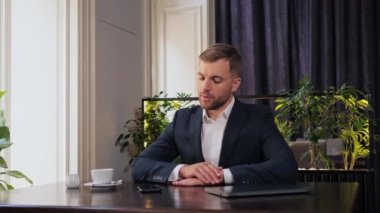 Nervous bearded businessman sitting in restaurant waiting business partner or waiter. Handsome male hand nervously drumming with fingers on restaurant table, looking at the mobile clock, havent time.