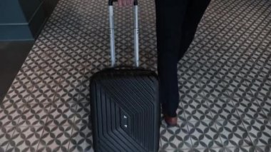 Elegant stylish businessman with travel suitcase walking at hotel lobby to reception. Traveling man with baggage settling in business hotel. Man arriving in hotel for business trip. Hotel concept