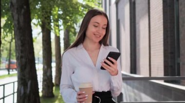 Ofis binalarının yanında şık gömlek giyen başarılı gülümseyen iş kadını portresi. Kadın gazete okuyor, sosyal medya akıllı telefonu dışarıda tutuyor. İş hayatı konsepti