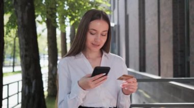 Kredi kartı ve cep telefonuyla tatmin olmuş güzel bir iş kadını internet üzerinden akıllı telefondan internet üzerinden ödeme yapıyor. Akıllı telefon Kara Cuma 'sı kullanan çekici bir bayan müşteri.