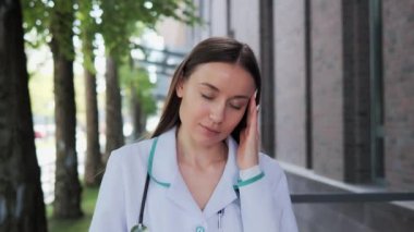 Stresli profesyonel doktor dışarıda baş ağrısı çekiyor, zor bir gün geçiriyor, çok fazla çalışmaktan gözlerim yoruldu. Aşırı yüklenmiş bir doktor hastanenin yakınlarında baş ağrısı çekiyor.