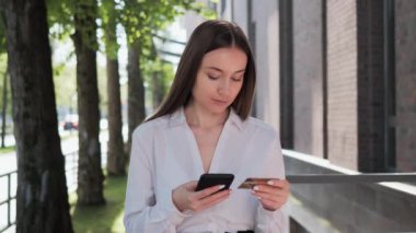 Güzel bir iş kadını internet üzerinden alışveriş yapıyor ya da cep telefonu uygulaması ve kredi kartıyla ödeme yapıyor. Bayan ofis çalışanı alıcı dışarıda banka kartına giriyor. İnternet bankacılığı, pazarlama