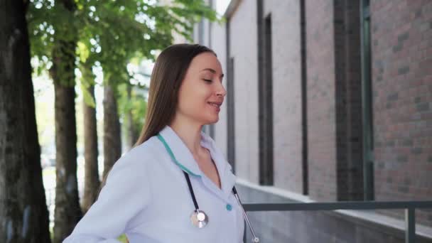 Gyönyörű Hosszú Hajú Doktornő Fehér Orvosi Kabátban Sztetoszkóppal Ahogy Kinti — Stock videók