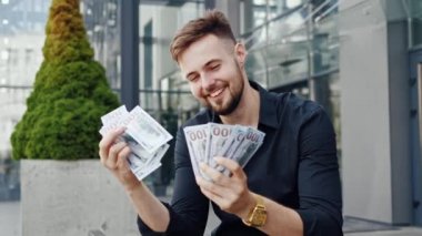 Erkek eli para sayıyor. Lüks saati olan mutlu genç bir adam nakit dolarları hesaplıyor. Profesyonel bir iş adamı dışarıda para tutuyor. Neşeli iş adamlarının kapanışı.