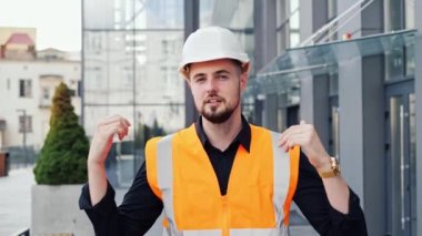 Modern cam bina ofisinin yanında duran profesyonel erkek mimar internette bir şeyler anlatıyor ya da video bloğu çekiyor. İş adamı ya da mimar, müşteri ya da patron için proje detaylarını anlatıyor