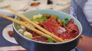 Geleneksel İtalyan jambonu, salam, peynir, zeytin roka ve grisini dilimli özel tepsi masası lüks restoran menüsü ile ziyafet masası hazırlayan garson, servis servisi.