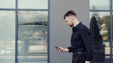Dışarıdan cep telefonuna bakan genç iş adamının yan görüntüsü