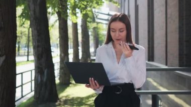 Çekici bir iş kadını bilgisayarla akıllı telefondan sesli mesaj kaydediyor.
