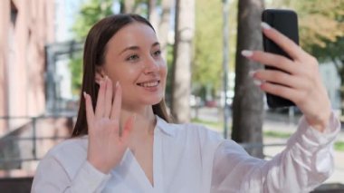 Neşeli mutlu iş kadını videosu açık havada cep telefonuyla sohbet ediyor.