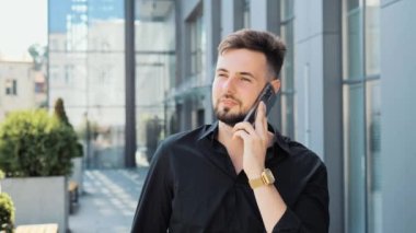 Yakışıklı, zeki iş adamı. Şehirde akıllı telefondan konuşuyor.