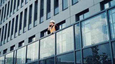 Ciddi mimar mühendisi konuşuyor. Terasta telefonla konuşuyor.