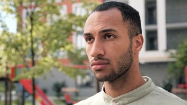 Genç Afro-Amerikan sakallı adamın yüzünü kapatıyoruz. Düşünceli bir şekilde yukarı bakıyor, temiz hava soluyor. Kendine güveni tam bir etnik adamın portresi. Şehir sokağında dikilip duruyor.