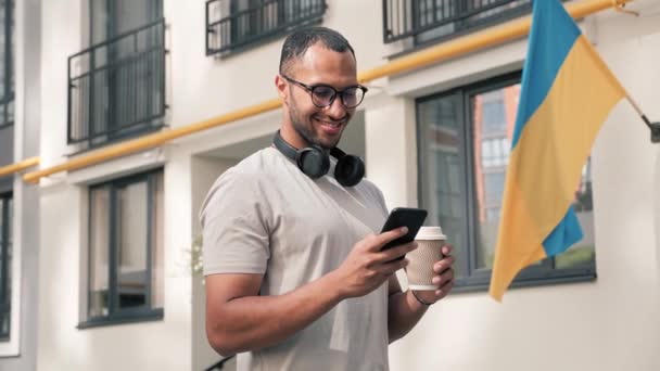 Joven Afroamericano Feliz Hombre Sosteniendo Teléfono Inteligente Café Con Ropa — Vídeo de stock