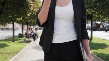 Kendine güvenen, kıvırcık saçlı, sorunlarını uzaktan çözen, ekibe sesli mesaj kaydeden şehir arka planında duran, çekim yapan, yavaş çekim yapan, kendine güvenen bir iş kadını.