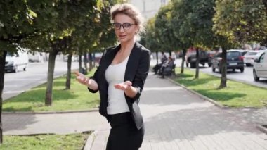 Güzel sarışın iş kadını kameraya döndü ve el hareketleriyle beni takip etti. Çekici bir kadın, gözlüklü büyüleyici bir gülümseme takıyor yaz gününün tadını çıkarıyor, başarılı insanlar.