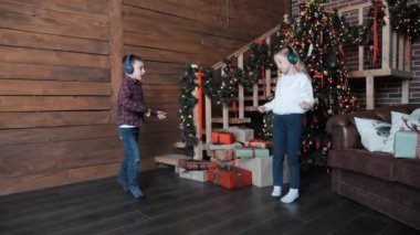 Kulaklıklı çocuklar müzik dinliyor, Noel Ağacı 'nın yanında dans ediyor. Küçük çocuklu mutlu bir aile Noel arifesini kutluyor. Şenlik zamanı.