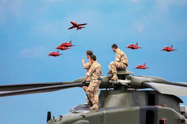 Команда вертолета смотрит выставку "Красные стрелы" — стоковое фото