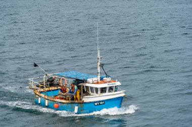 Whitby, North York, İngiltere - 19 Temmuz 2022 'de Whitby, Kuzey Yorkshire' a doğru giden balıkçı teknesi. Kimliği belirsiz iki adam.