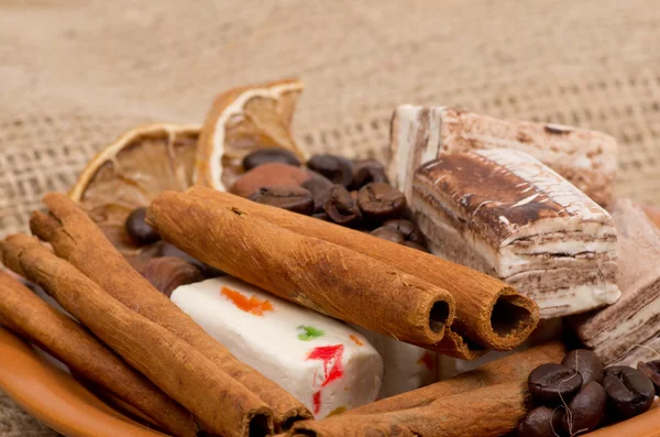 Süßigkeiten, Zimt, Nüsse und Kaffeebohnen auf einer Untertasse — Stockfoto