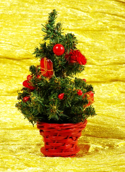 Kleiner geschmückter Weihnachtsbaum auf goldenem Hintergrund mit Geschenken — Stockfoto