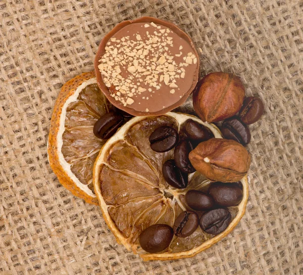 Sweet, lemon, nuts and coffee beans on burlap — Stock Photo, Image