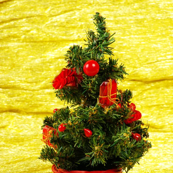 Pequeño árbol de Navidad decorado sobre fondo dorado con regalos — Foto de Stock