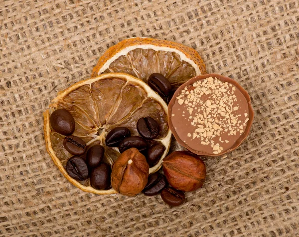 Sweet, lemon, nuts and coffee beans on burlap — Stock Photo, Image