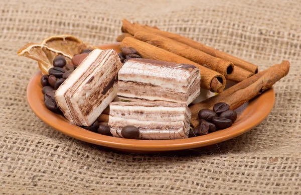 Sweets, cinnamon, nuts and coffee beans on a saucer — Stock Photo, Image