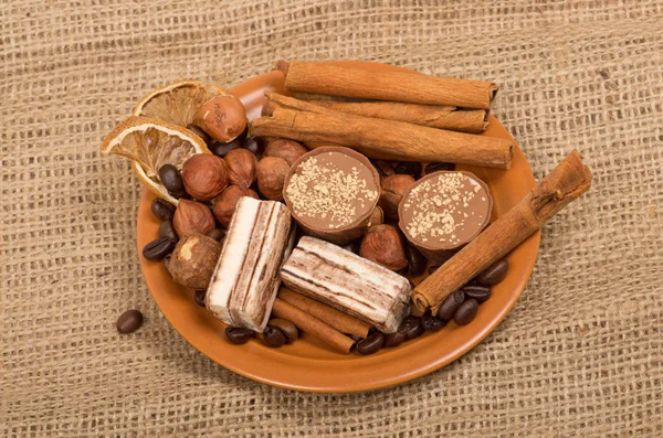 Słodycze, cynamon, orzechy i ziarna kawy na spodek — Zdjęcie stockowe
