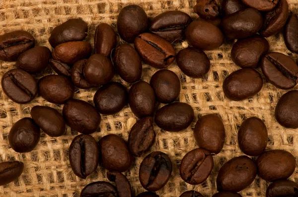Kávové zrna pozadí na pytlovina — Stock fotografie
