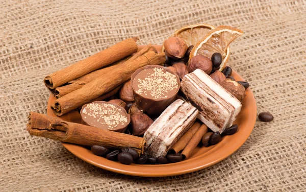 Sweets, cinnamon, nuts and coffee beans on a saucer — Stock Photo, Image