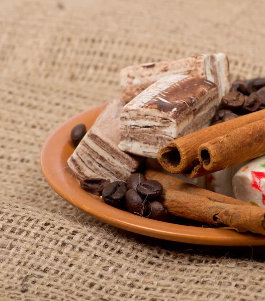 Snoep, kaneel, noten en koffiebonen op een schotel — Stockfoto