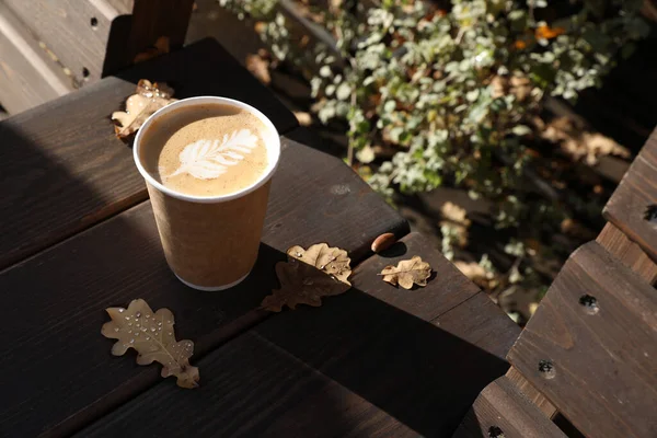 Bir sonbahar günü tahta bir bankta kağıt bardakta kahve.
