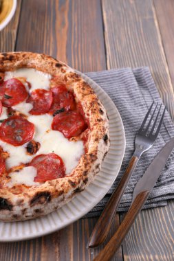 Pepperoni ve sebze salatalı Napoli pizzası.