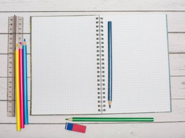 Ahşap masaya renkli kalemler ve not defterleri.