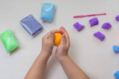 Çocuk elleri renkli kille oynuyor. Ev yapımı plastik. Plastiksin. Hamur oyna. Kil kalıbı yapan kız. Ev yapımı kil.