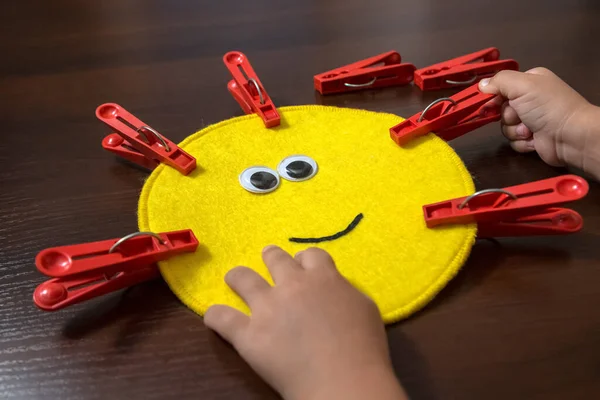 Anaokulu çağındaki küçük bir kızın elleri. Renkli zarlar ve mandallarla ilgili ders. Duyusal gelişim, iyi motor beceriler, Montessori yöntemi, Araçlar, Çocuk Geliştirme konsepti.