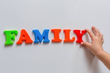 Aile kelimesi bir çocuğun el yazısıyla yazılmış renkli manyetik harflerden oluşur. Aile Günü.